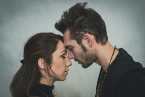 A photo of a man and woman touching foreheads and looking sad